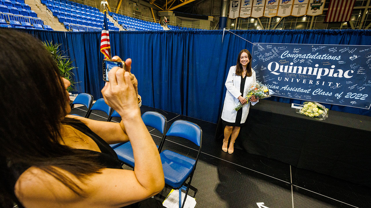 Graduate poses for a photo on stage