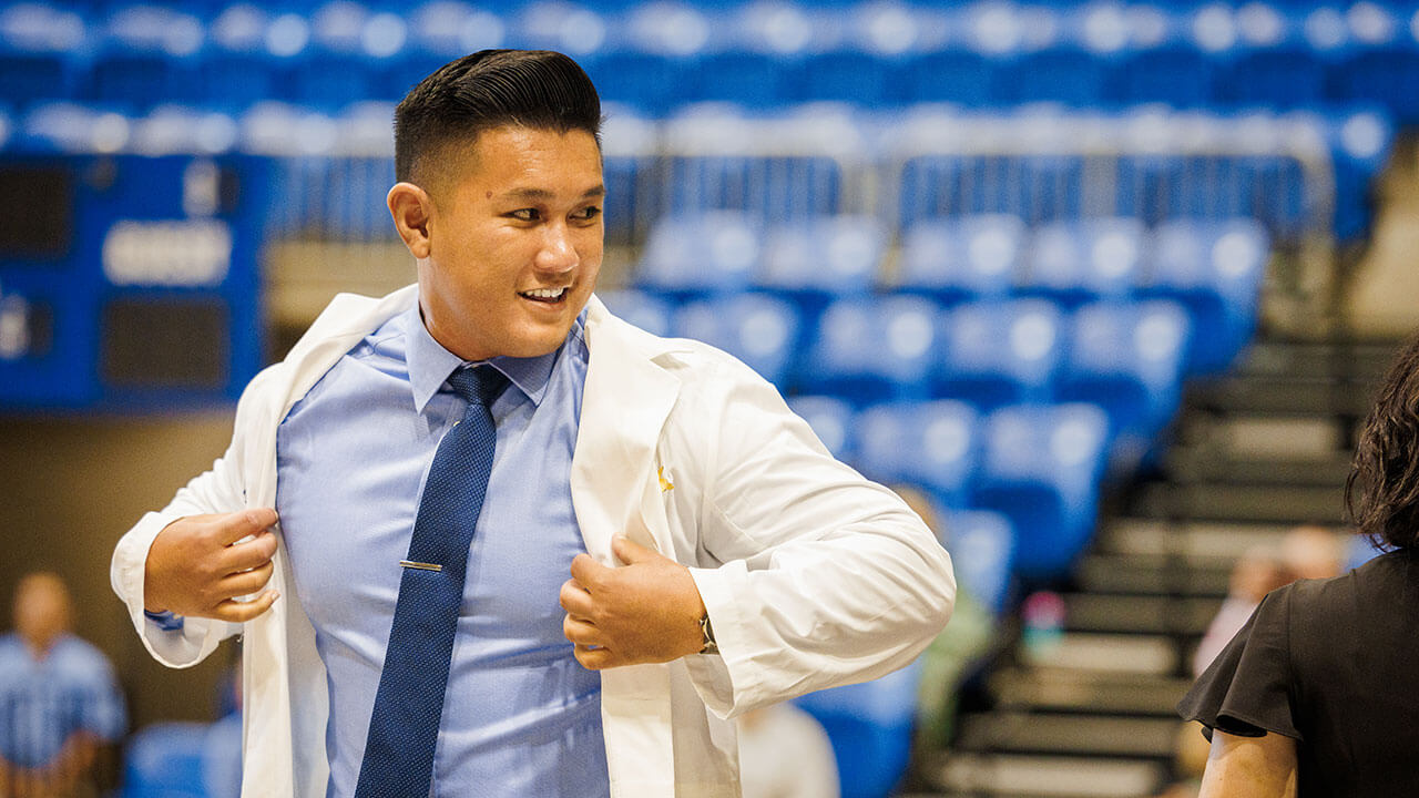 Student smiles as he walks across stage