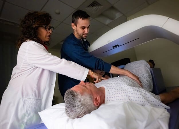 Medical imaging student and professor perform a procedure on a patient.