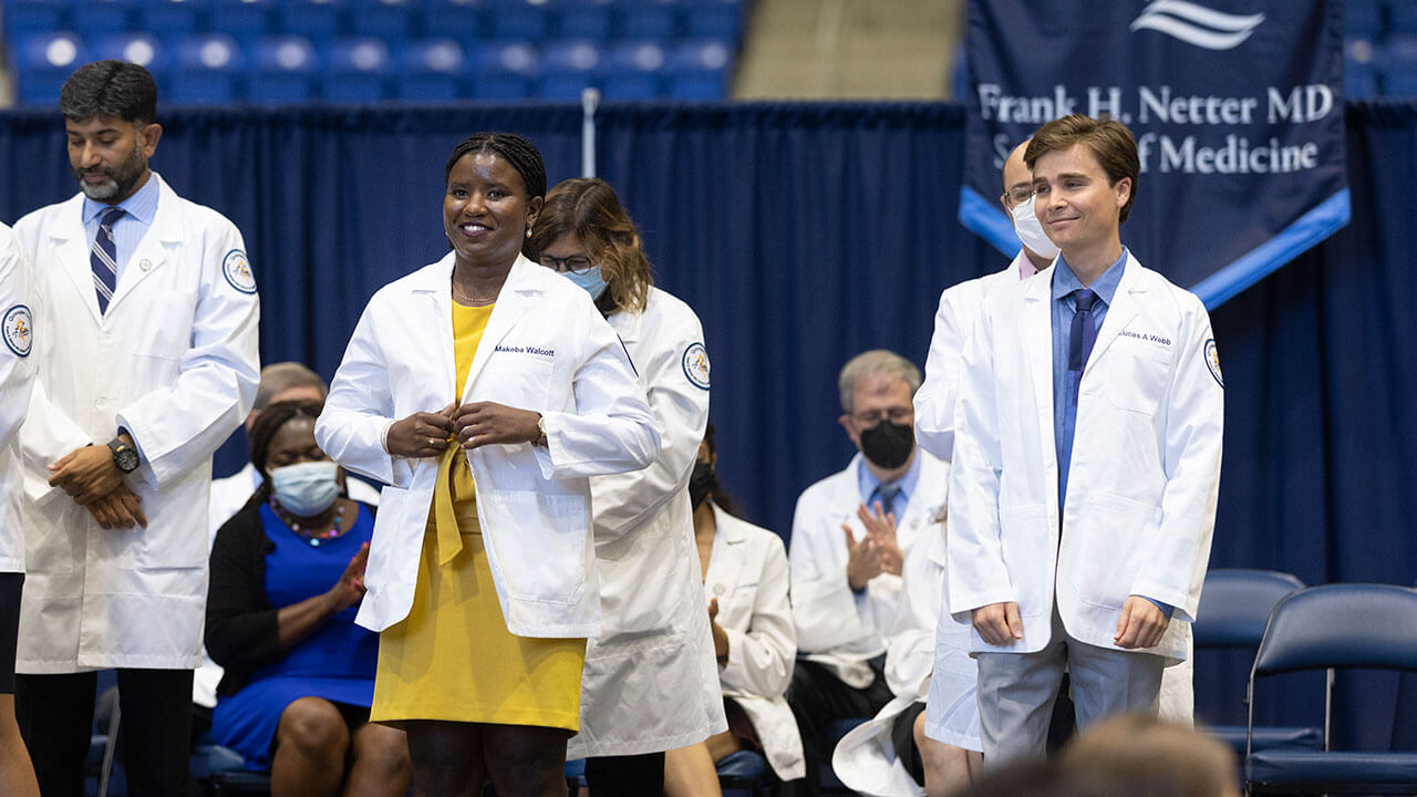 Students receive their white coats on stage