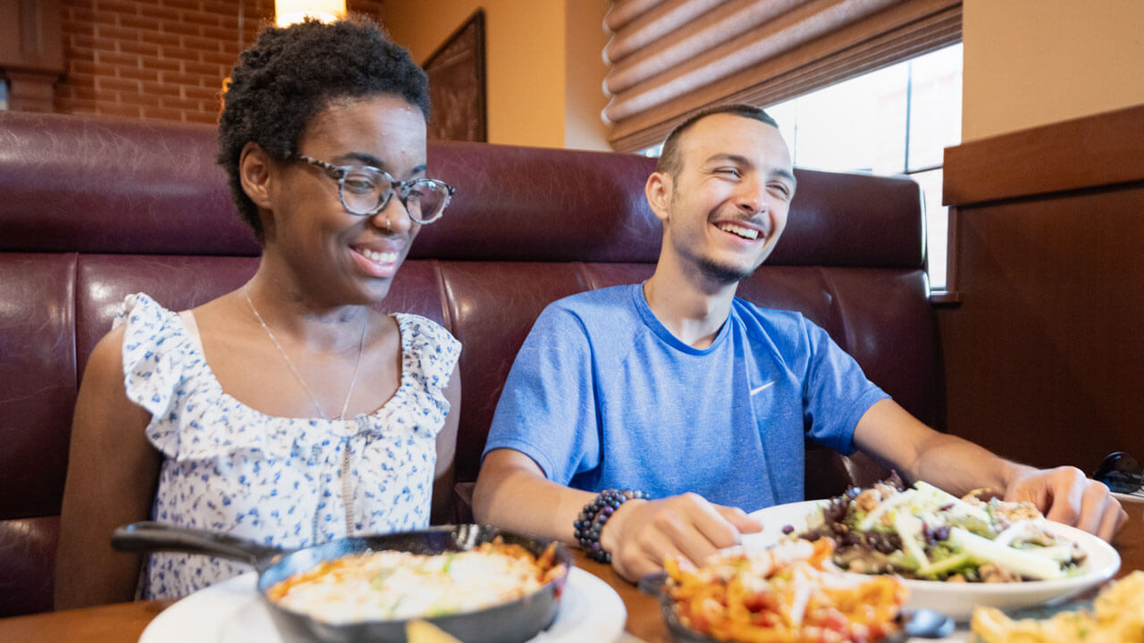 Two friends laugh while they enjoy Elis on Whitney for lunch