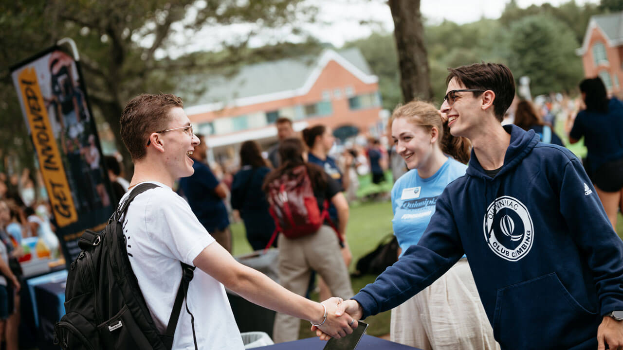 Students shake hands at a packed student engagement fair