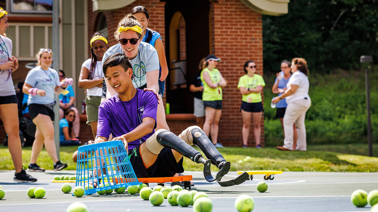 A camper picks up tennis balls during a group activity