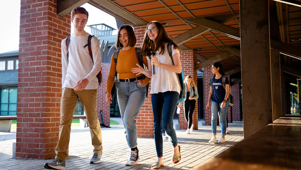 Three students walking around campus and talking