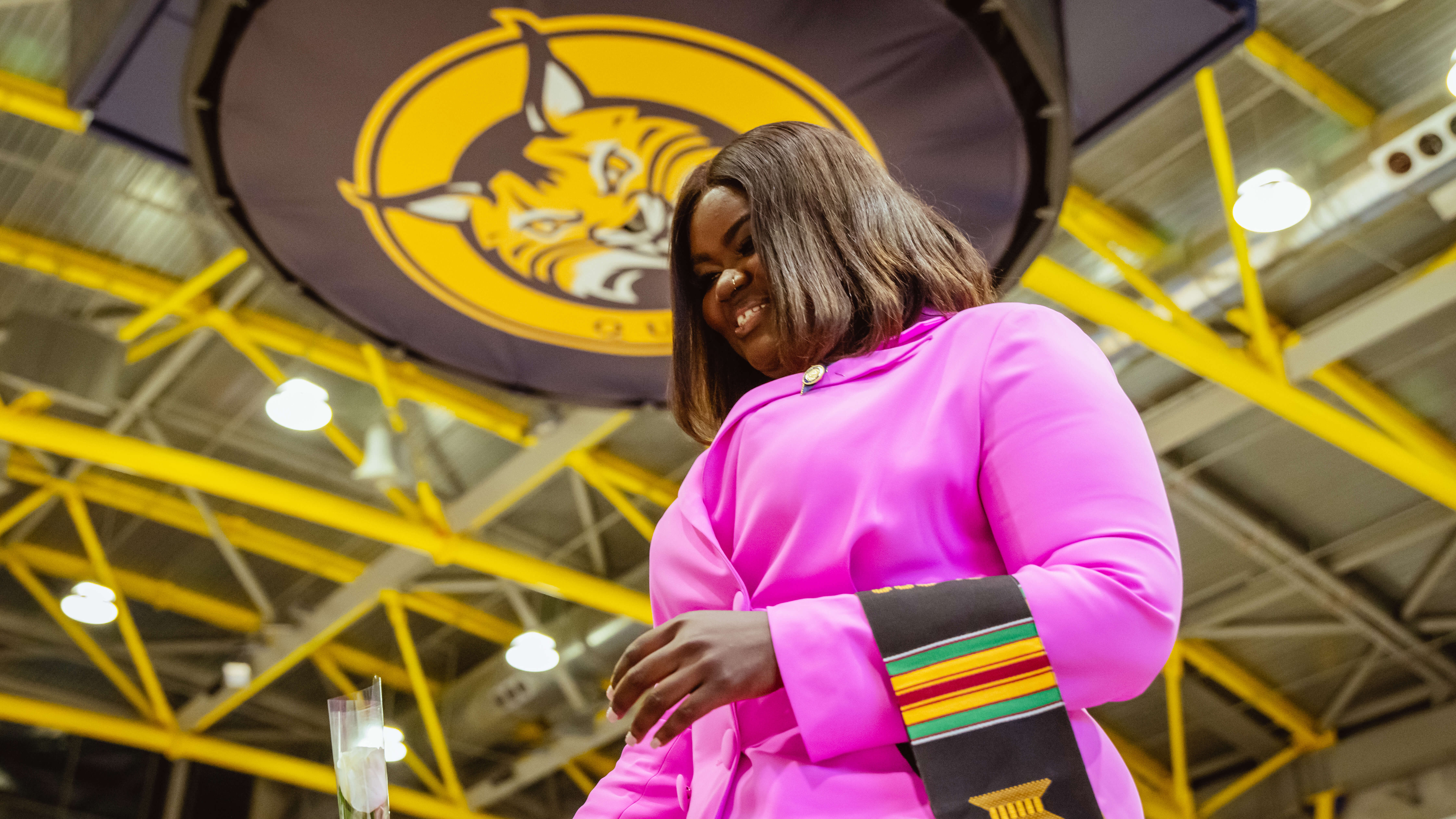 A graduate walks across the stage with her pin on