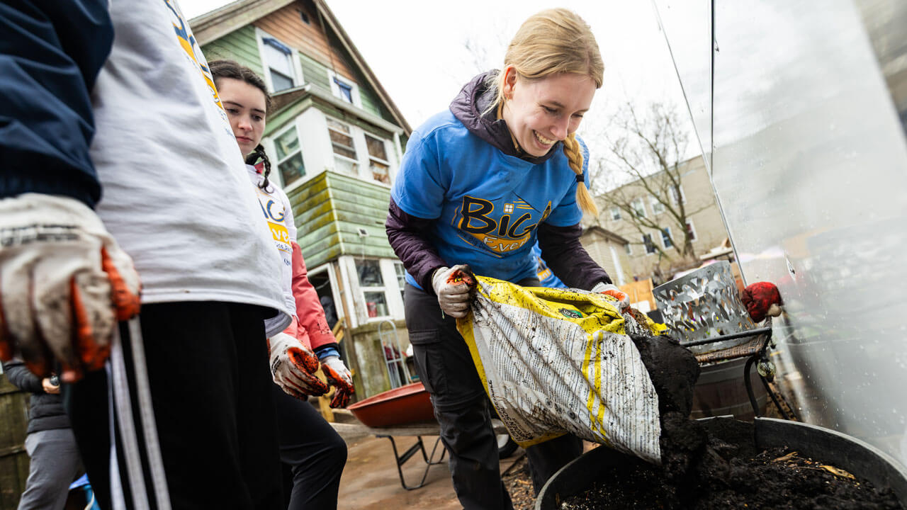 Student pouring soil into a pot at Big Event