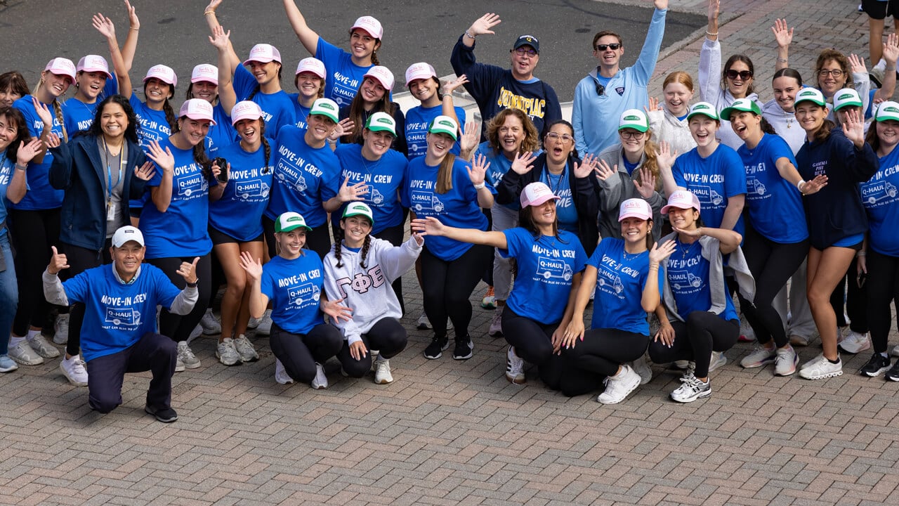 Dozens of students and staff volunteering during first-year move-in cheer in matching shirts