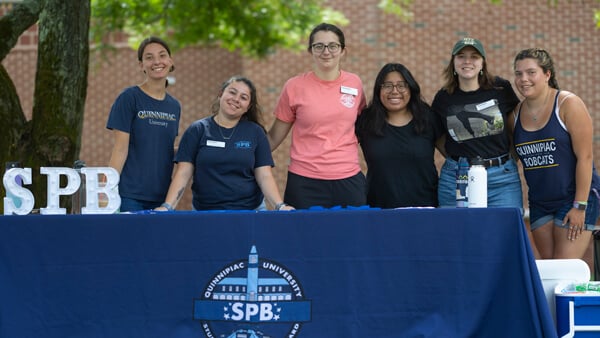 Members of the Student Programming Board pose for a photo at an activity table