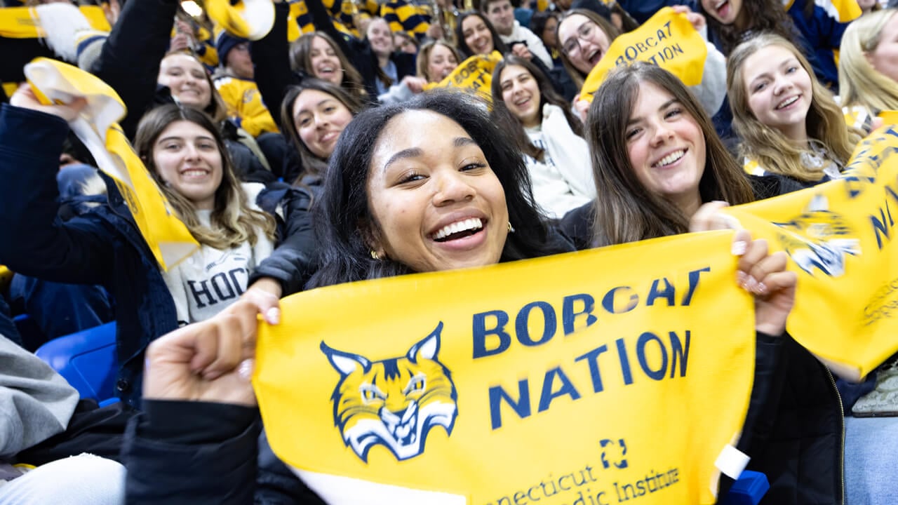 Bobcats fans cheer and hold up Bobcat Nation rally towels in the hockey stadium