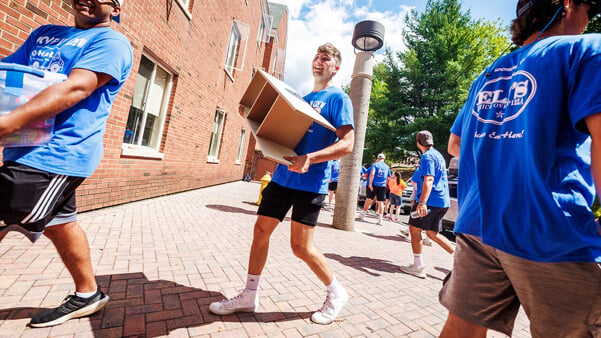 Students carry in boxes to a residence hall on move-in day