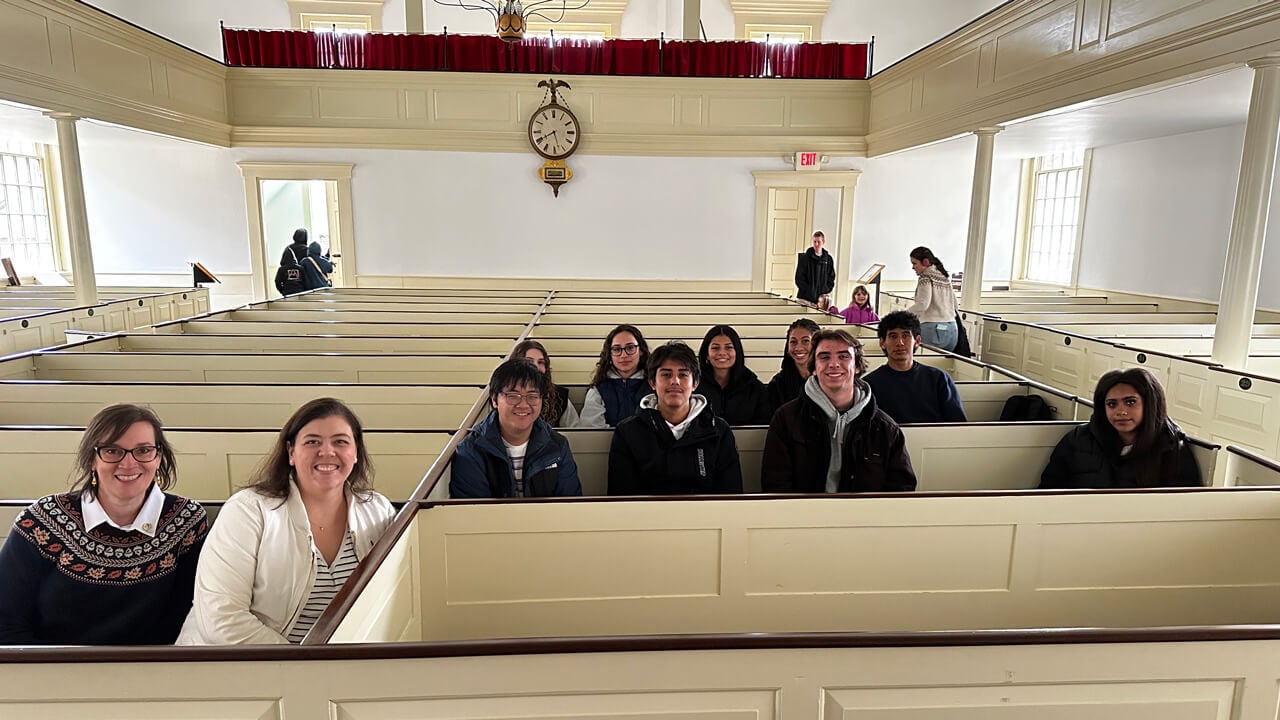 A group of students and faculty sitting in the pews of an old-fashioned church.