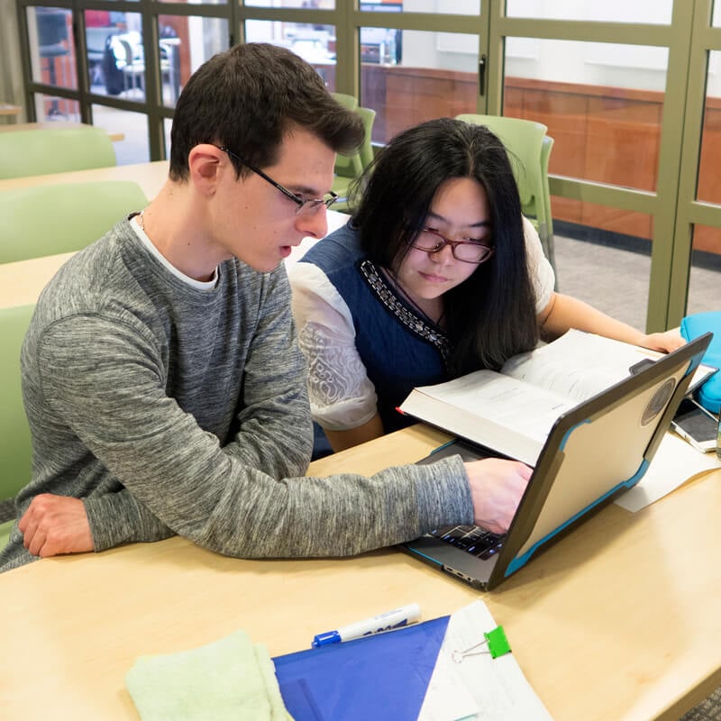 A student and peer mentor work on a laptop in the Quinnipiac Learning Commons