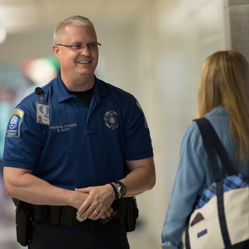 A public safety officer speaks with a student in a hallway