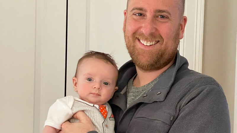 Daniel Black smiles broadly while he holds his infant son