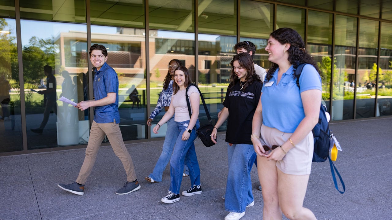 Students walk and talk in front of The Site