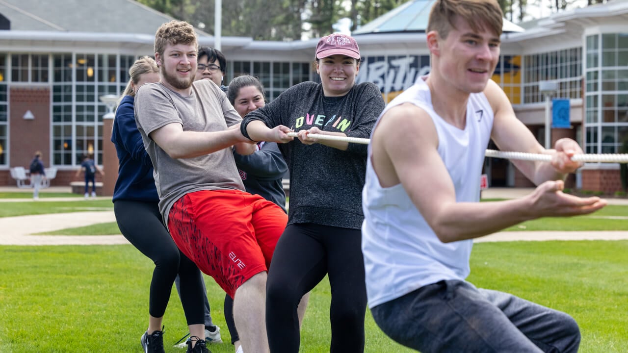 Fraternity and sorority members play tug-of-war in front of the Mount Carmel Campus Student Center.