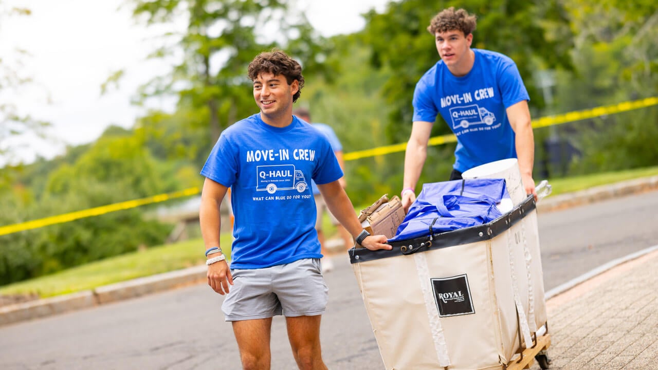 Students push a cart full of items.