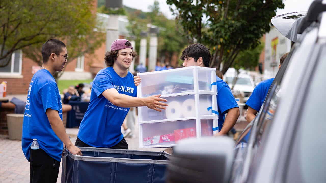 Students help unload items out of cars.
