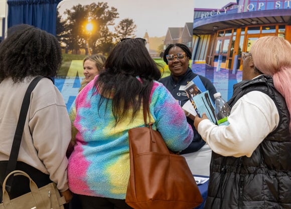 An admissions counselor speaks with a prospective student in front of a Quinnipiac display