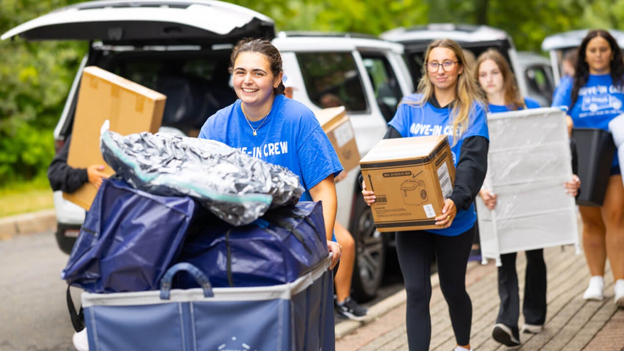 Students carry boxes and items.