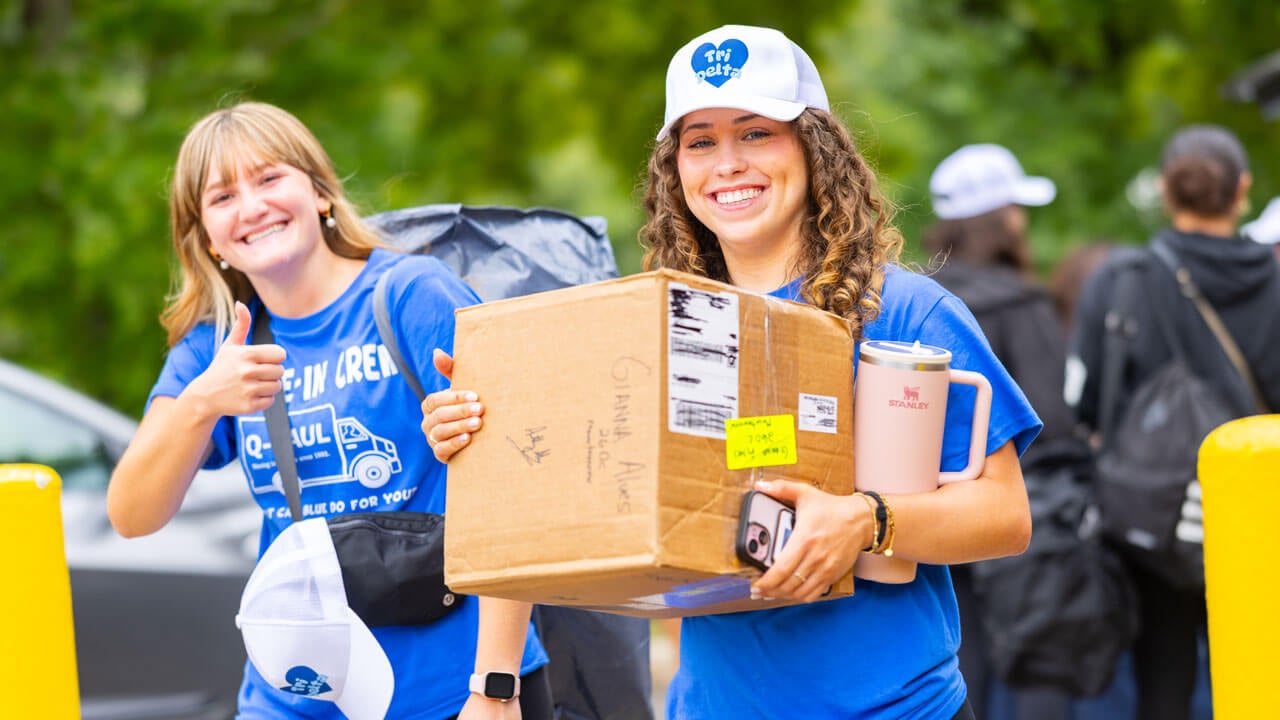 Students carry boxes and items.