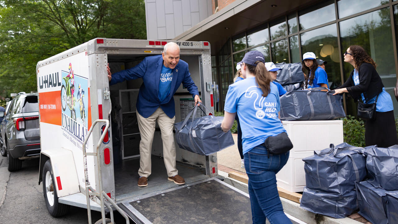 Students help unload items from cars.