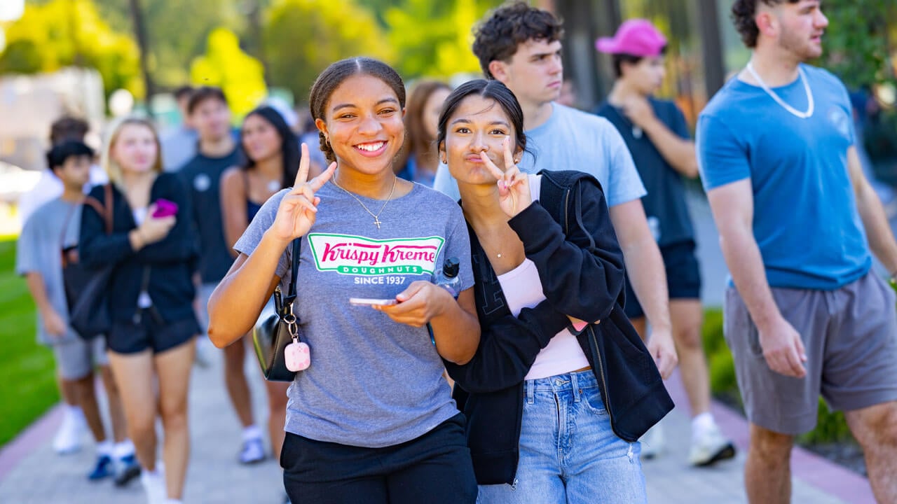 Two first-year students smile and hold up a peace sign