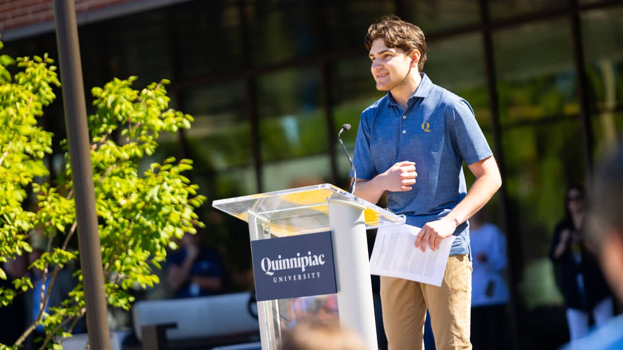 Student speaking to the class of '29 at a podium on South Quad