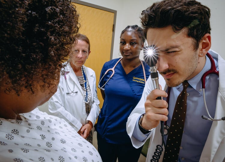 A nursing student performs an eye exam on a standardized patient.