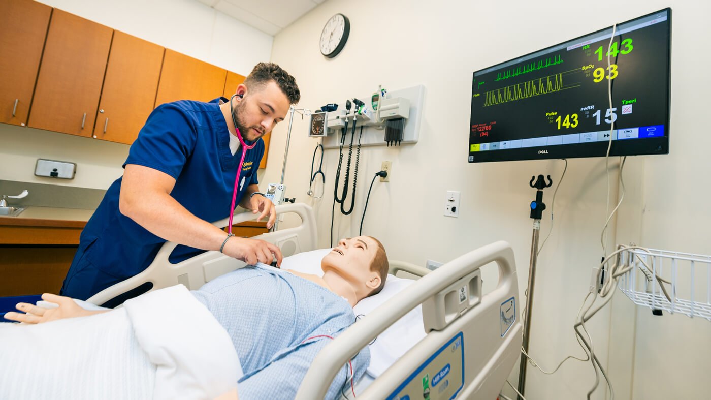 A nursing student listens to a manikin patients' heartbeat with a stethoscope in a North Haven campus simulation lab.