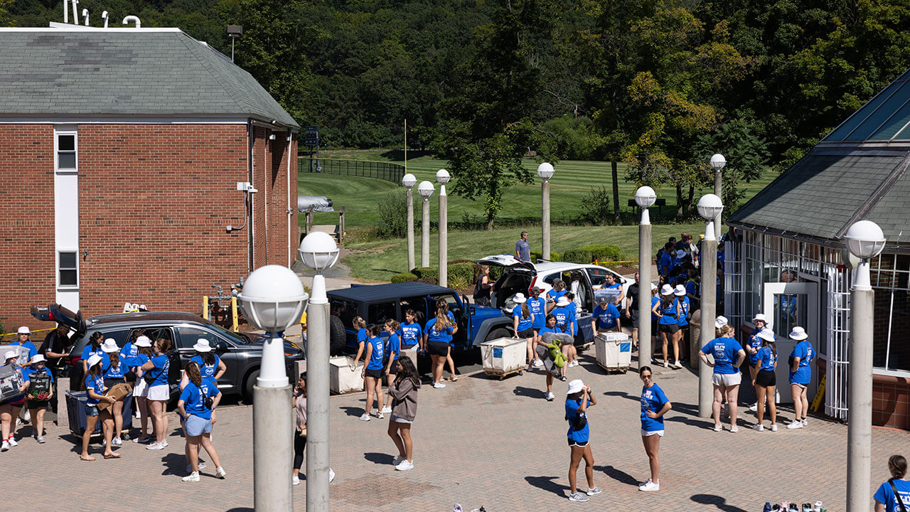 Students in the move-in crew stand outside in Bobcat Way unloading cars