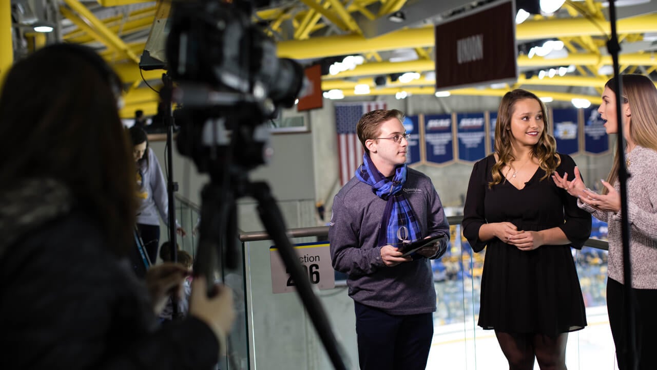 3 students speak on camera in the hockey arena