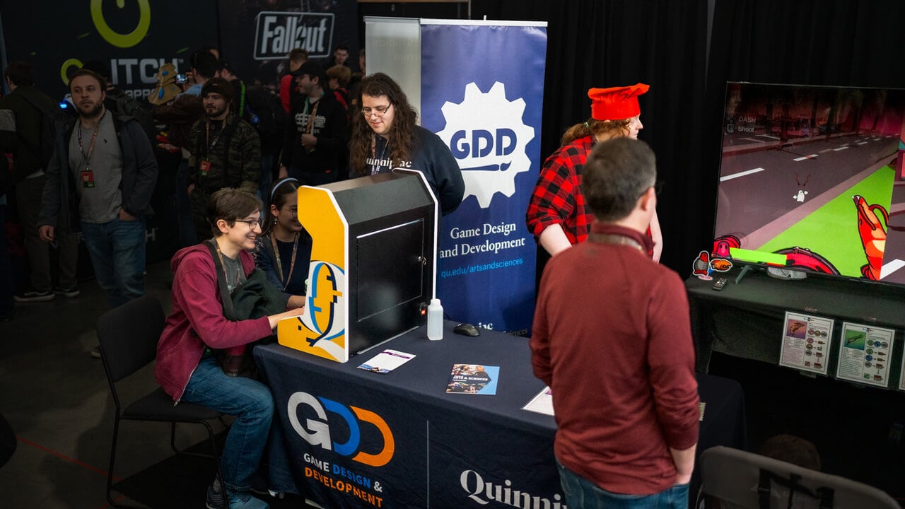 Three participants grouped around Quinnipiac's miniature gaming console.