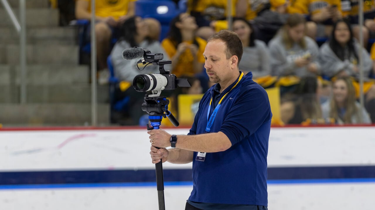 A man holding a camera in a hockey rink