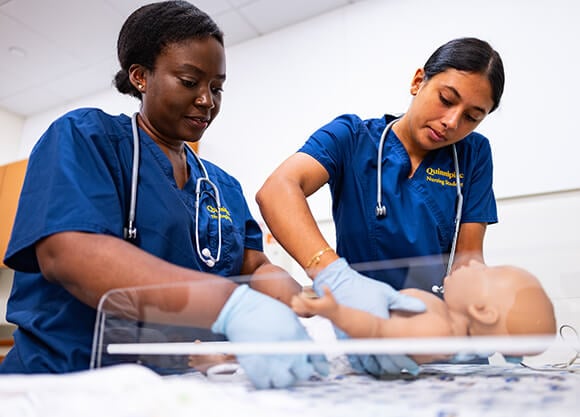 Two nursing students working with a simulation pediatric patient
