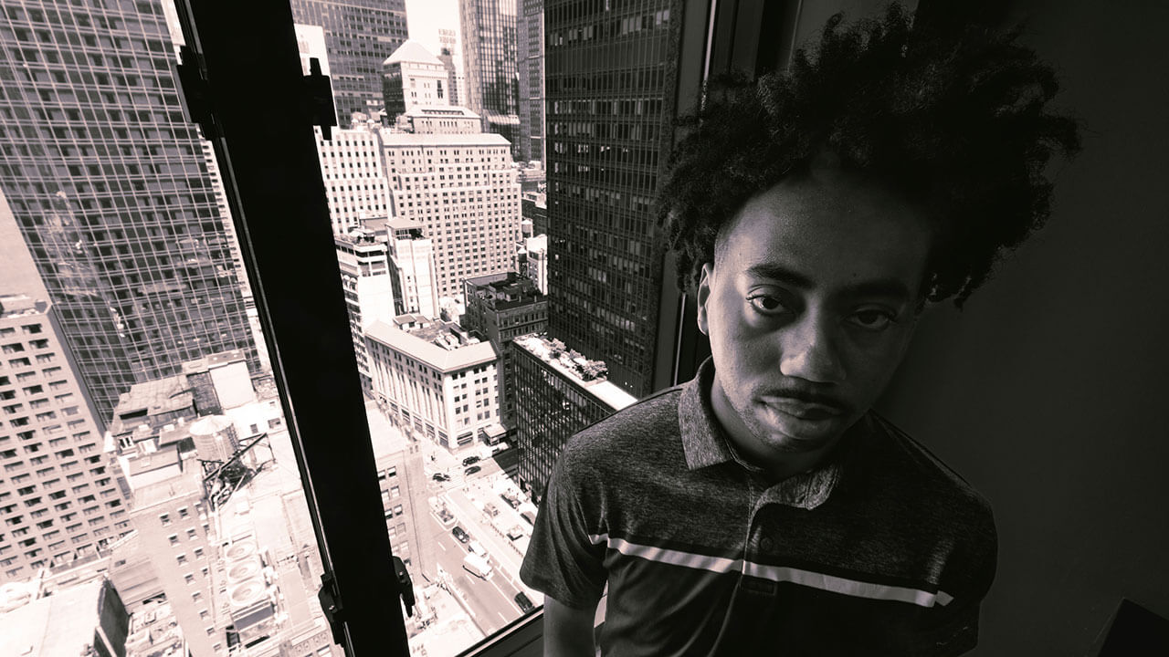 Black and white image of Toyloy Brown in front of a window looking out at skyscrapers