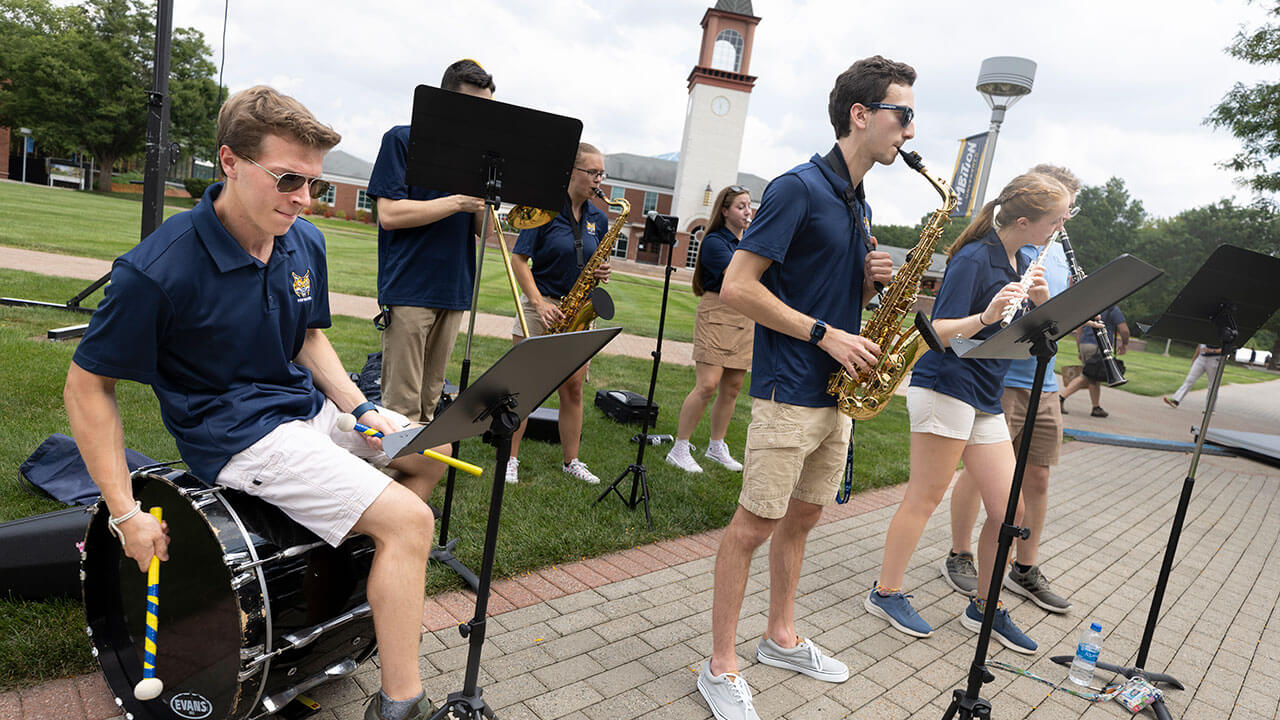 The pep band plays their instruments on the quad