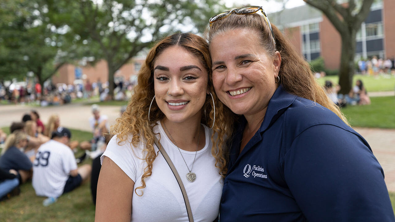 A student poses for a photo with a staff member on the quad