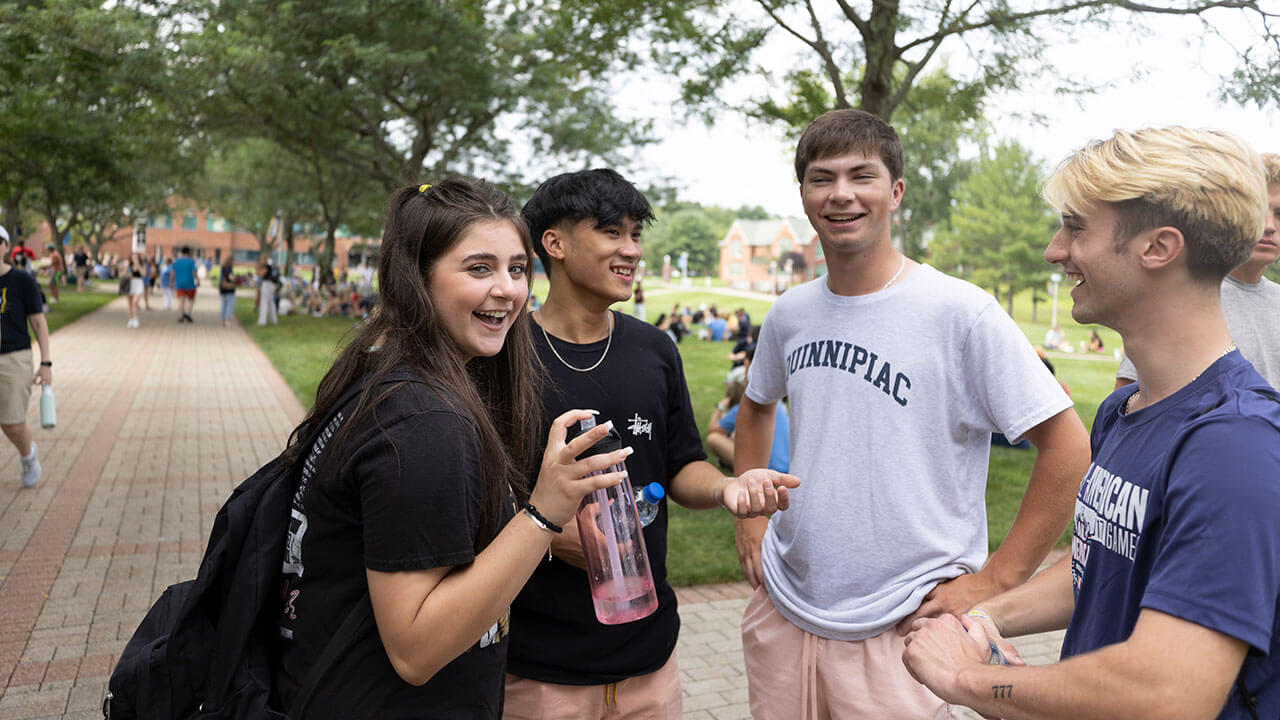 A group of new students laugh as they talk on the quad
