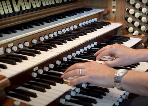 Close up of hands playing on organ keyboards