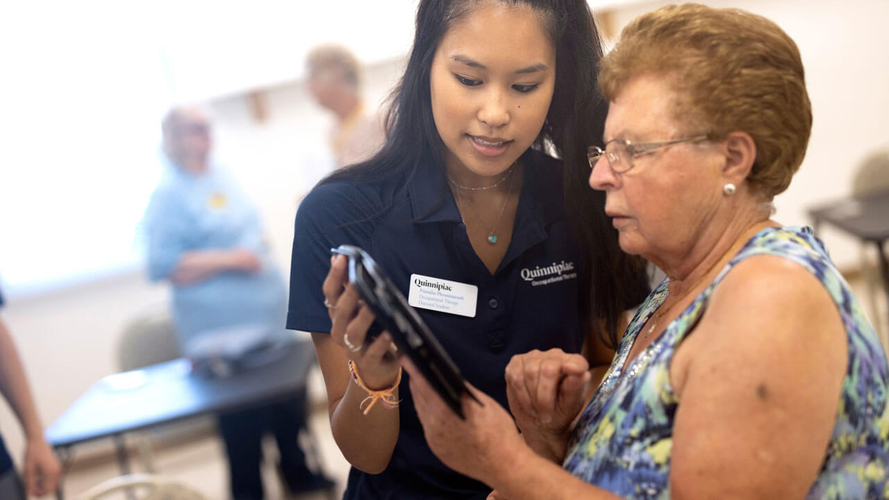 An occupational therapy student works with a senior citizen on a tablet computer