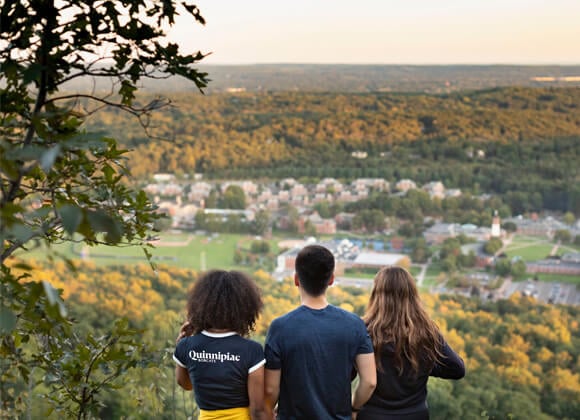 Three students looking off into the distance on top of Sleeping Giant State Park.