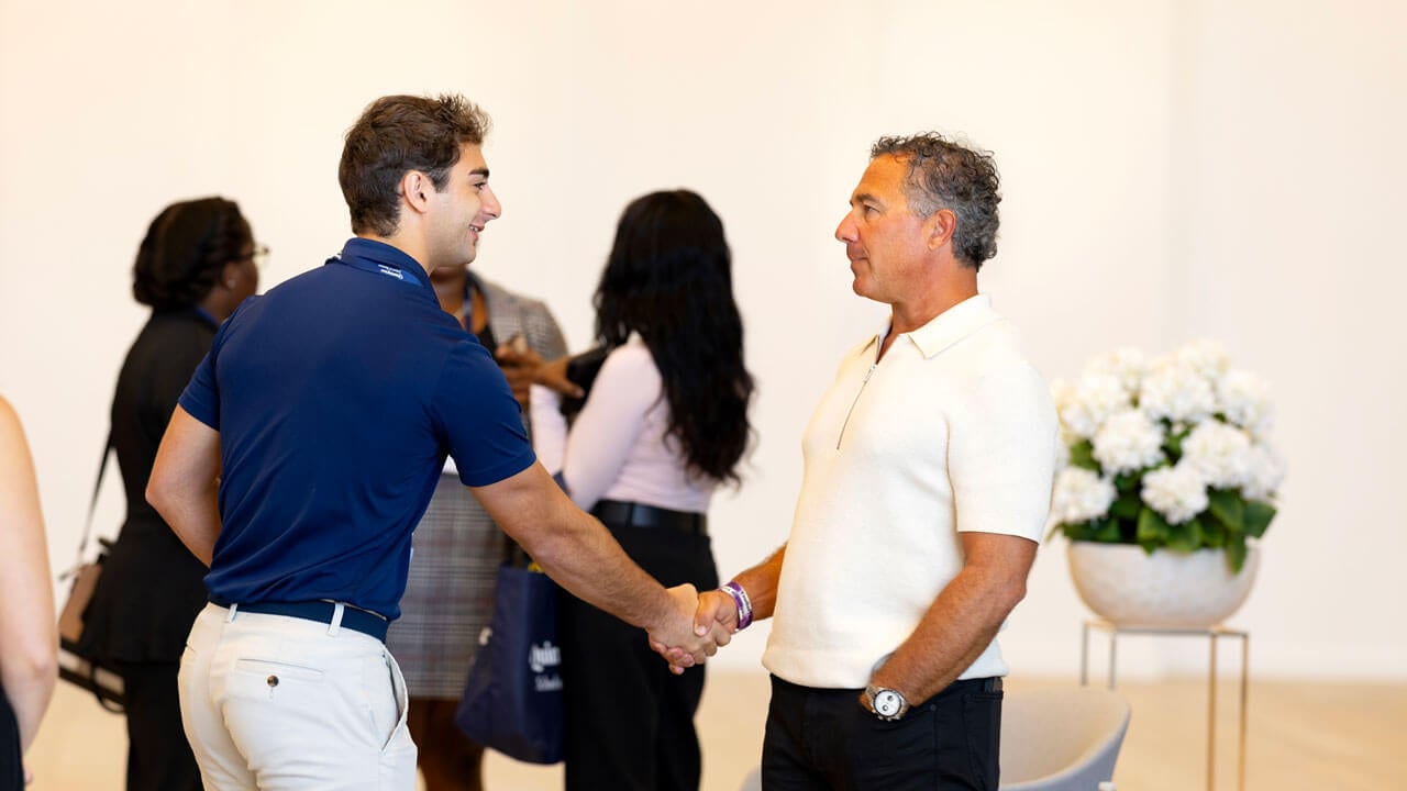 Chuck Saia shakes hand with student