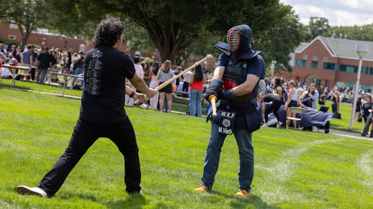 Students from the fencing club duel on the lawn