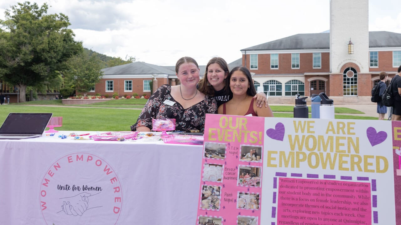 Students smile behind their women empowerment table