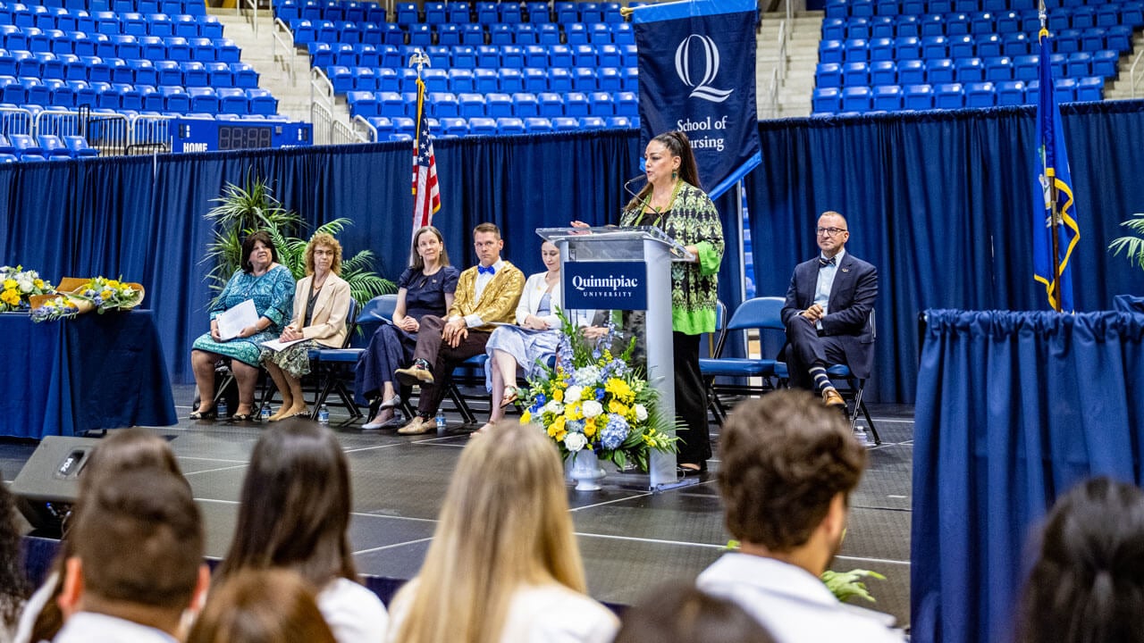 Speaker stands at a podium in the M&T Bank Arena at the 2025 pinning ceremony