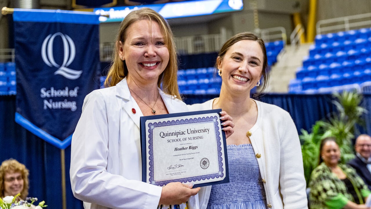Two women stand while holding a diploma
