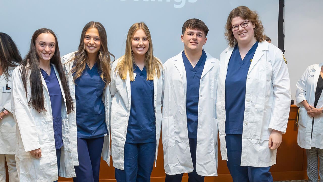 five nursing students pose in their new white coats