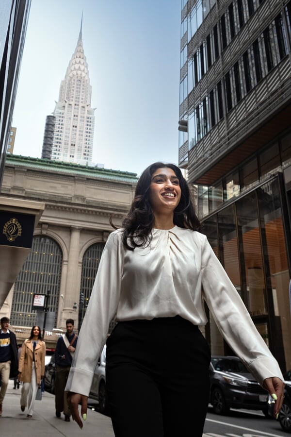 Woman walking in NYC, with the Empire State Building in the distance.