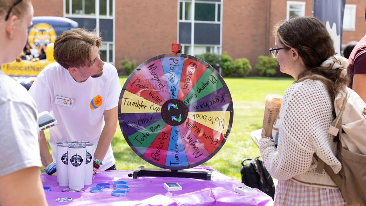Students spin a wheel at an engagement fair table